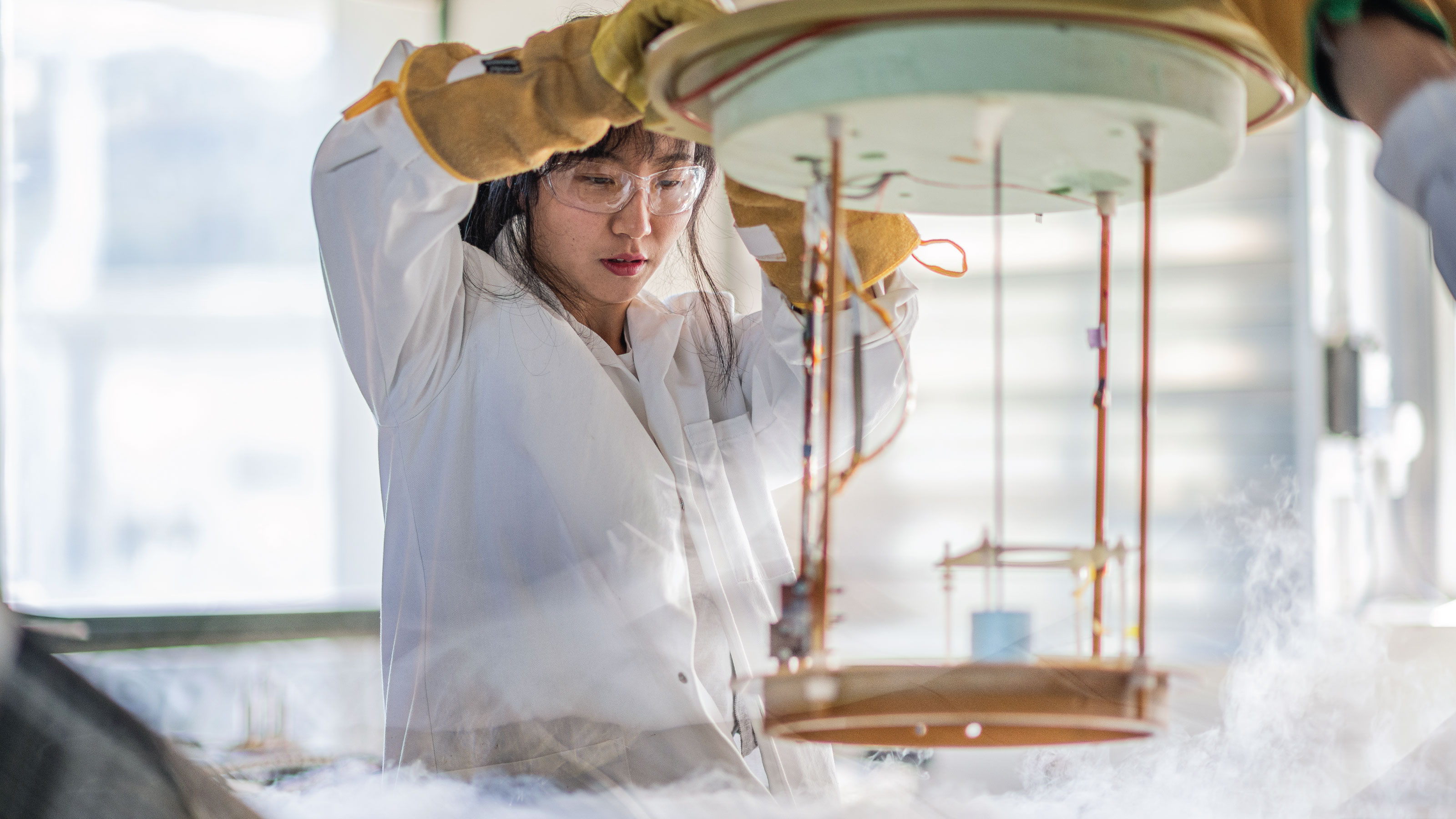 Postgraduate student wearing a lab coat and protective gloves and glasses