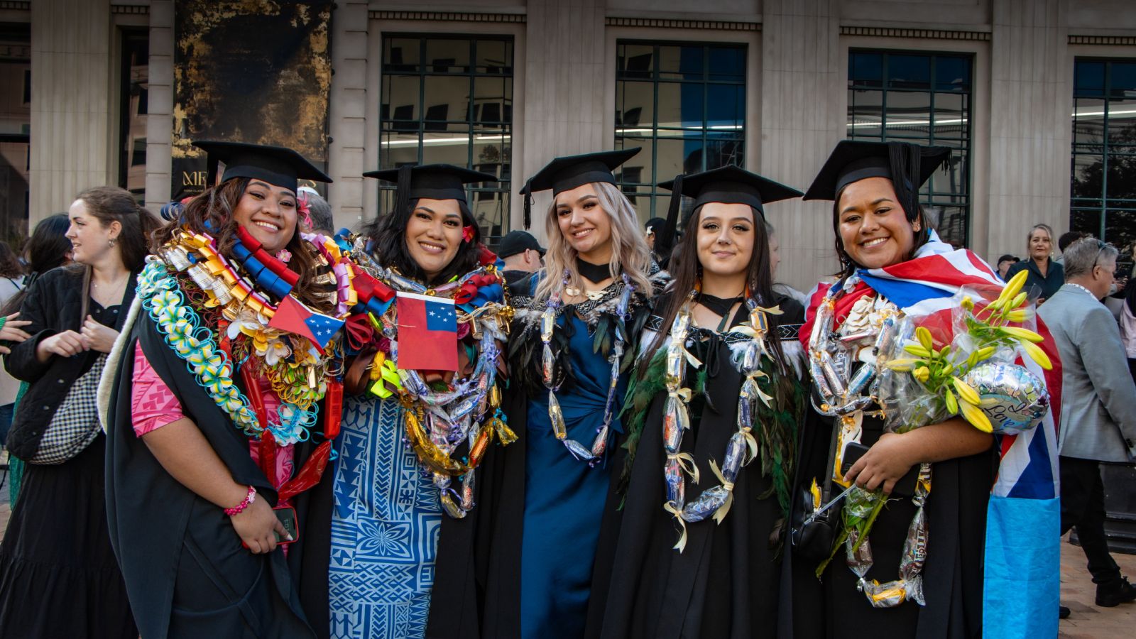 Five women in graduation garb smiling at camera