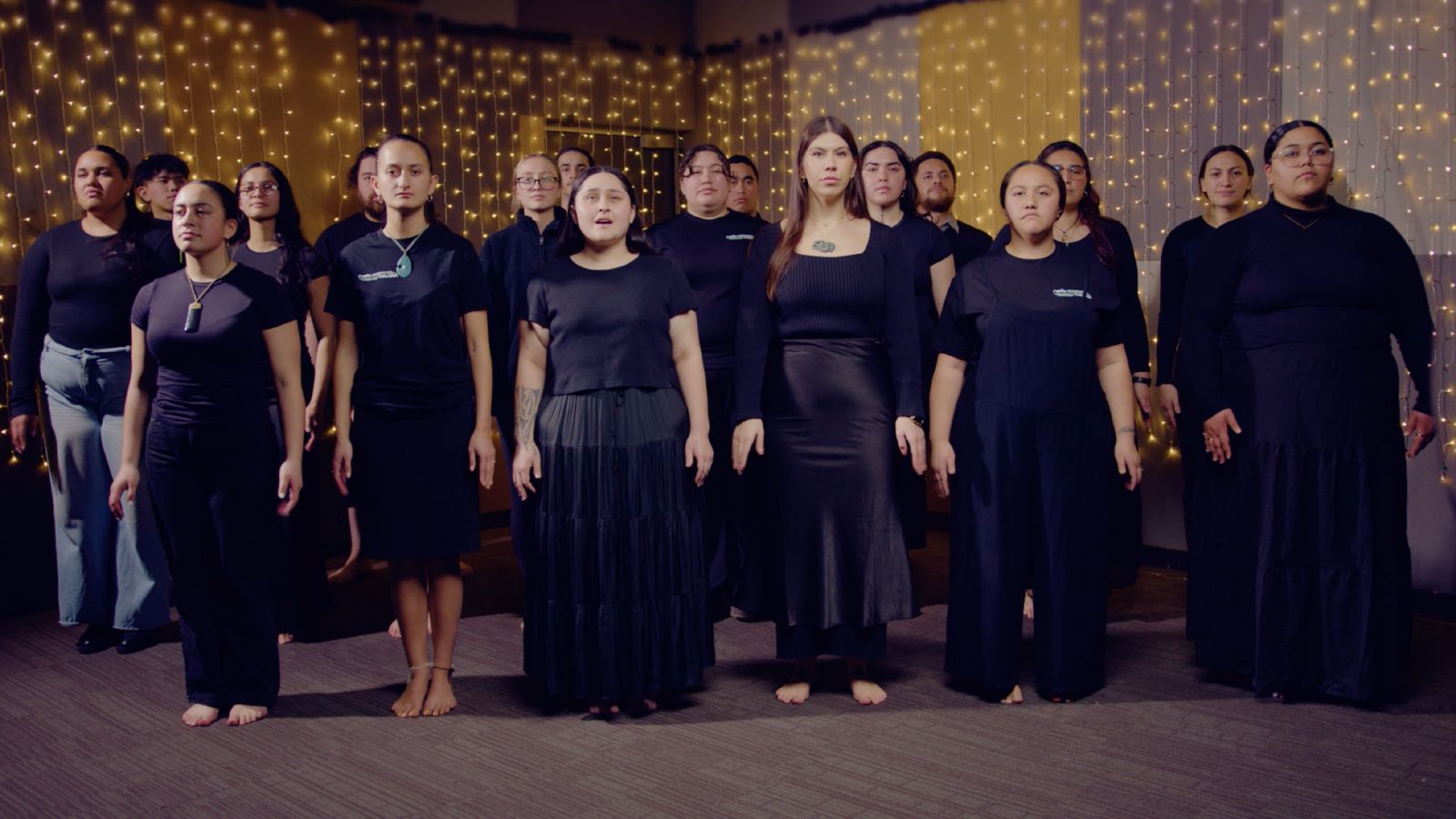 A large group of women dressed in black doing a performance.