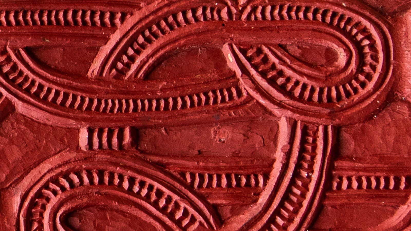 A close up of a red wooden carving at the marae