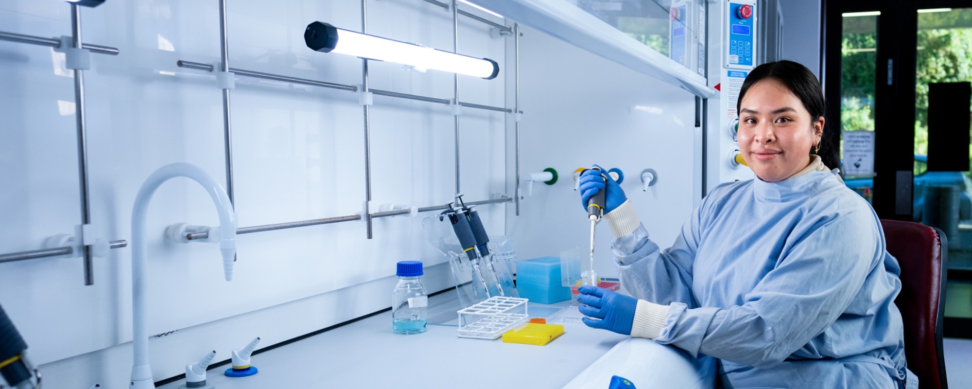 A woman a lab wearing a lab coat and holding equipment.