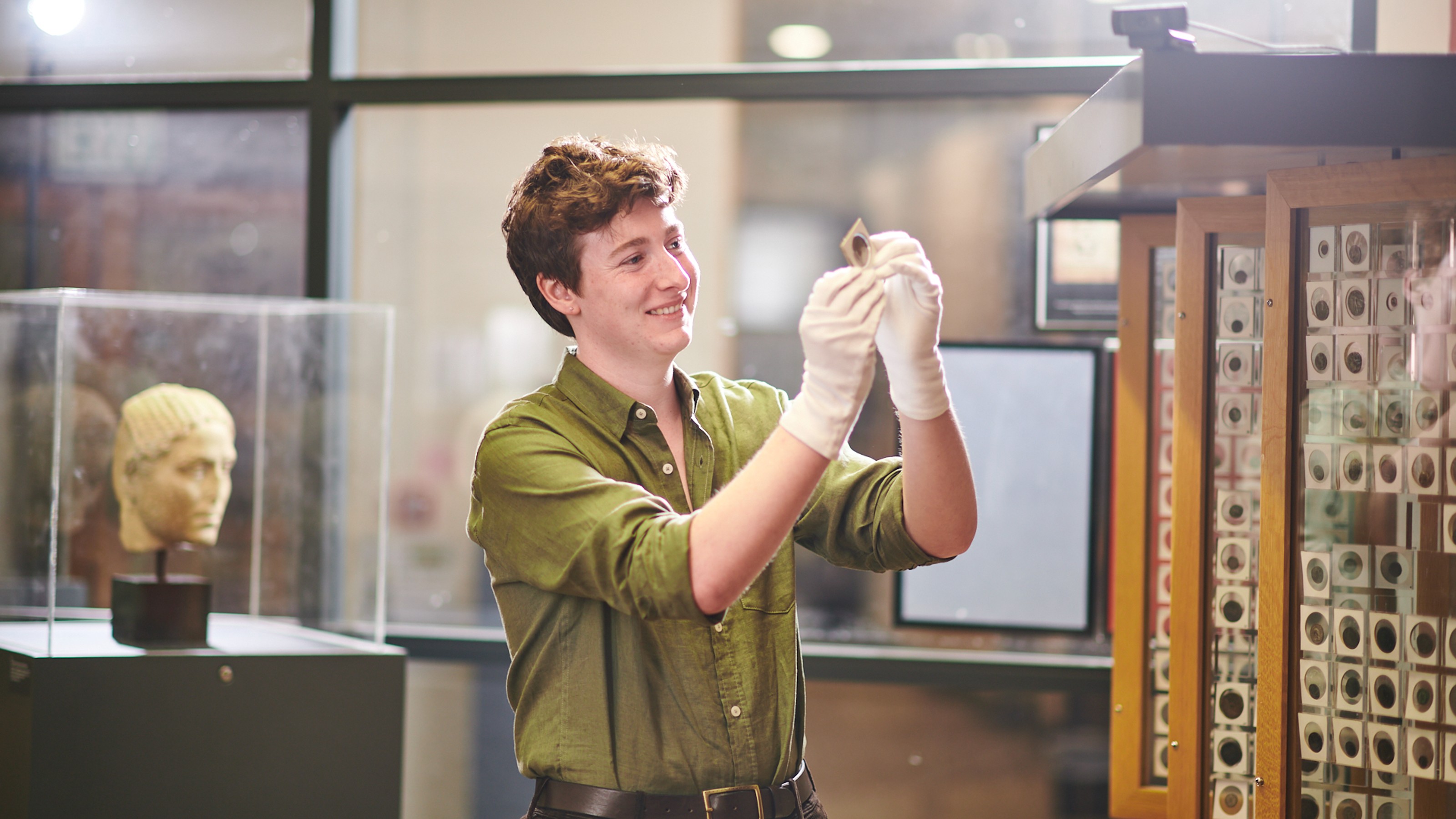 Classics student Alex Davey studies an ancient coin in the Classics Museum at VUW.