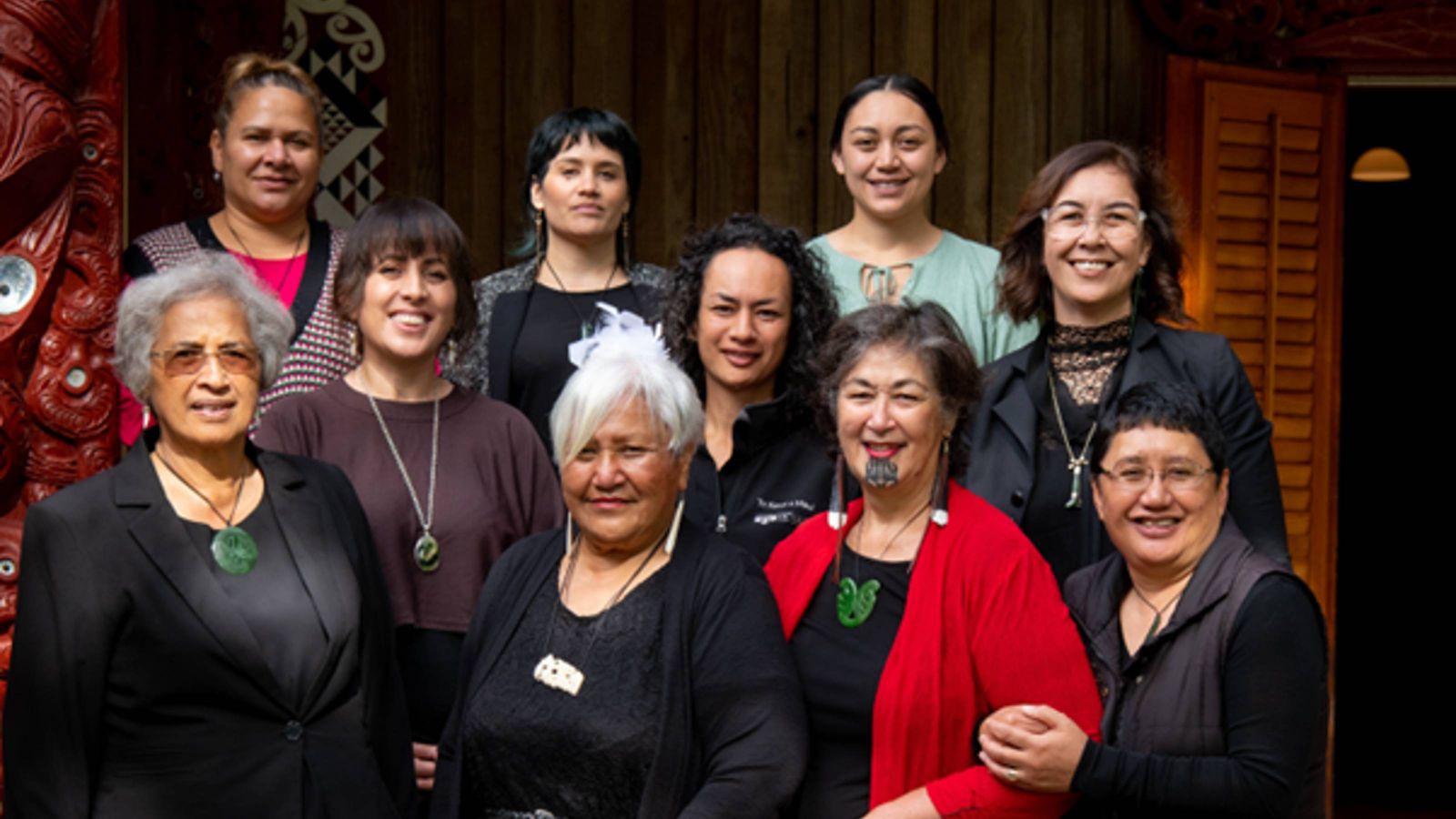 Portait of 10 wahine Māori gathered in front of the wharenui