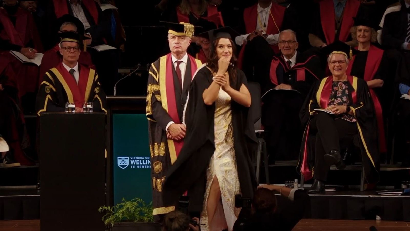 A woman dancing on stage after graduating.