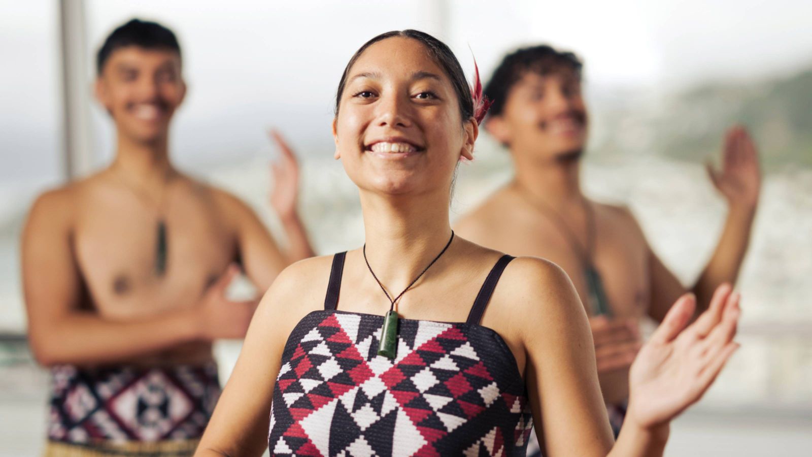 Three students doing kapa haka wearing traditional dress