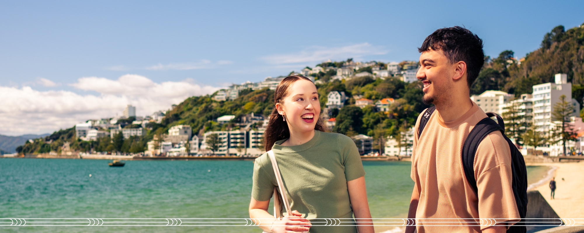 Two students walking along a city beach