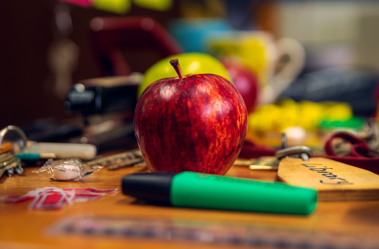 Image of a desk with keys, stationary and an apple.