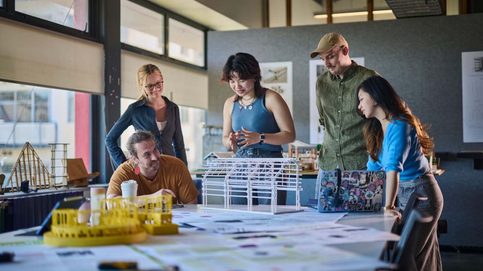 A group of students standing around a desk with building models