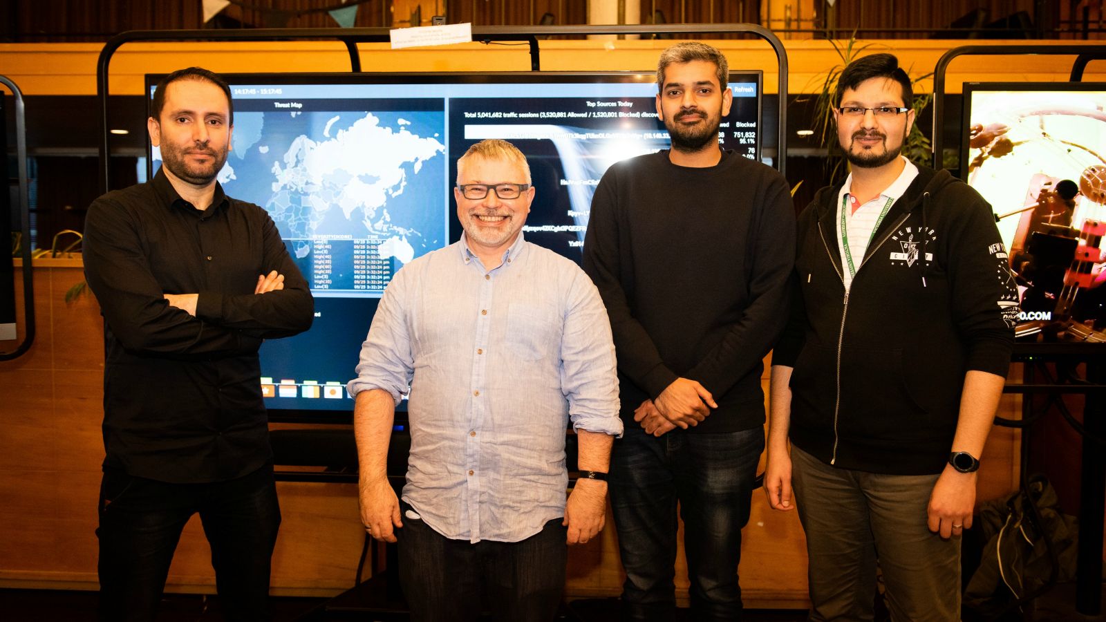 Four academics in front of a cybersecurity map – Some of the ECS cybersecurity team. From left: Dr Masood Mansoori, A/Prof Ian Welch, PhD candidate Junaid Haseeb, and Dr Harith Al-Sahaf.