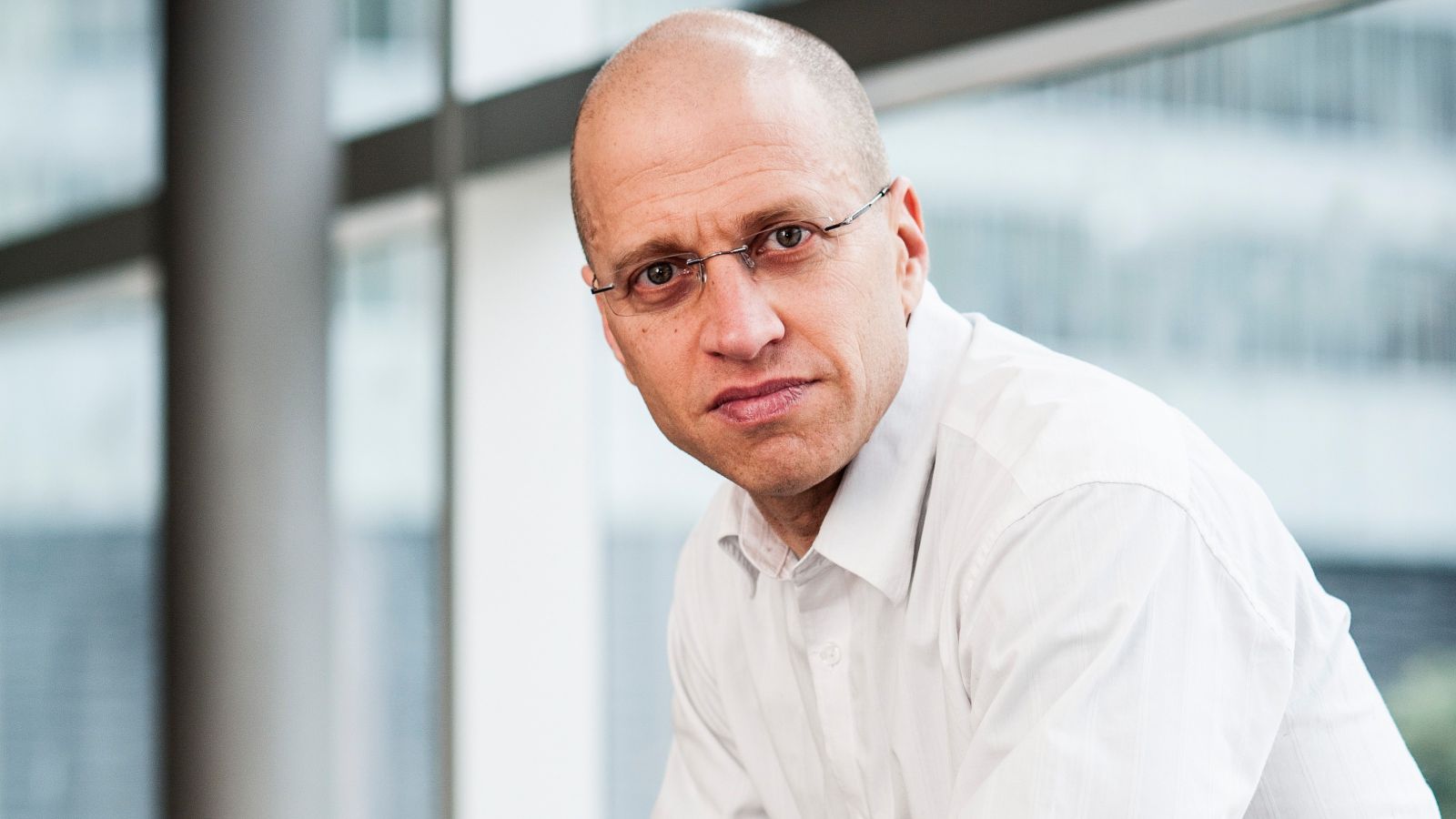 Close-up of Professor Ilan Noy sitting by a window wearing a white shirt.