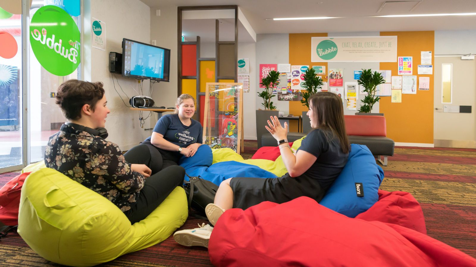 Three people talking, sitting in a circle on bean bags.