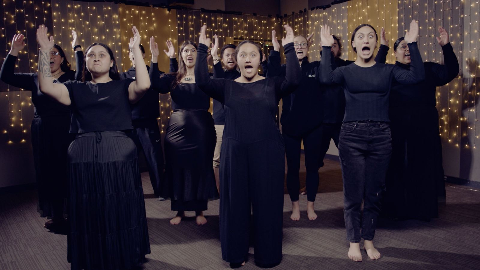 A group of women with their hands in the air performing a song.