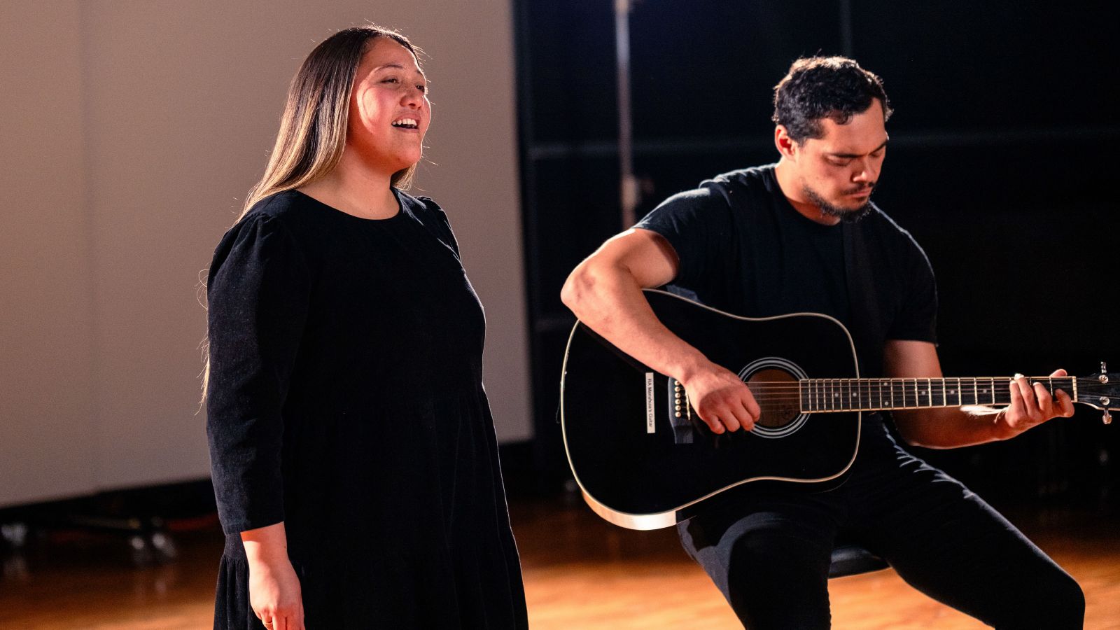 A man playing an accoustic guitar accompanied by a woman singing.