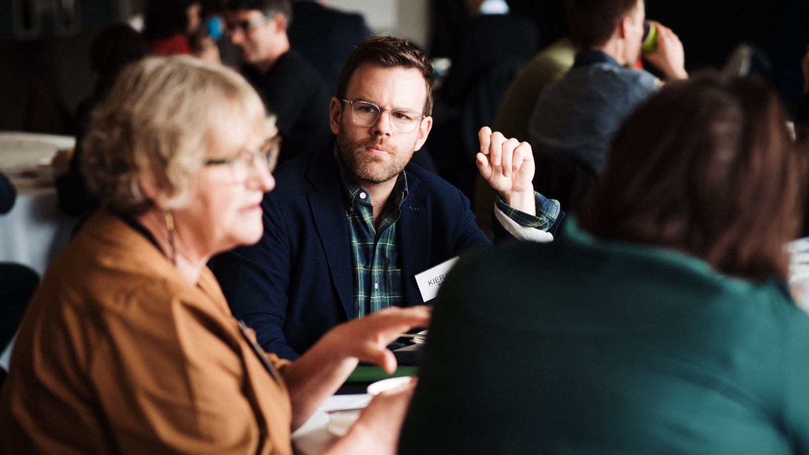 Researcher focusing their attention on another researcher in a room of seated people