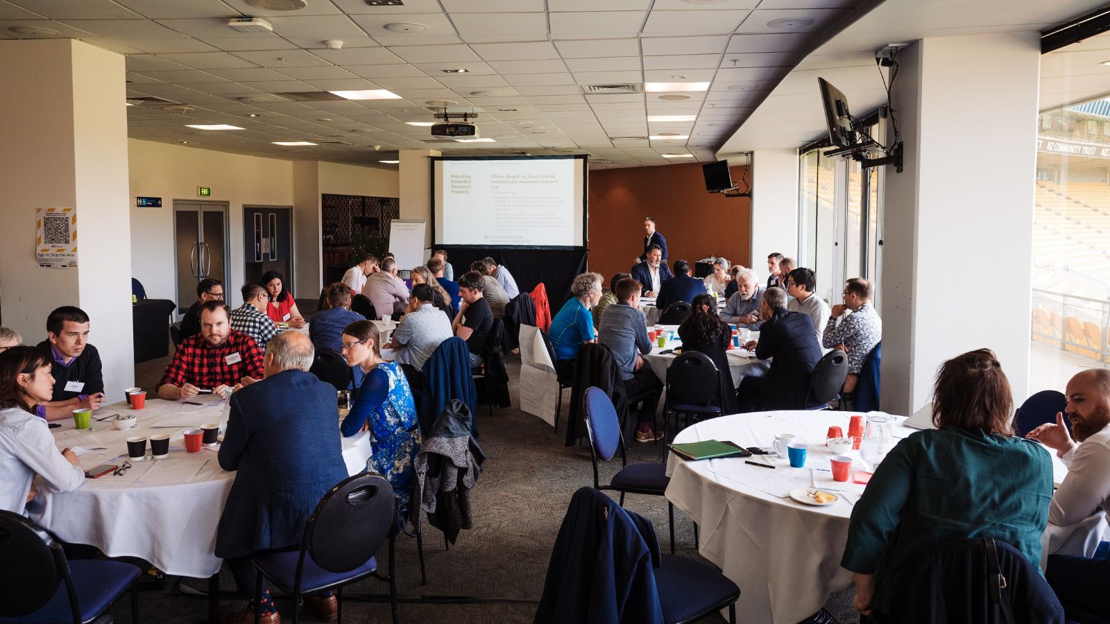 Groups of people seated at round tables talking to each other