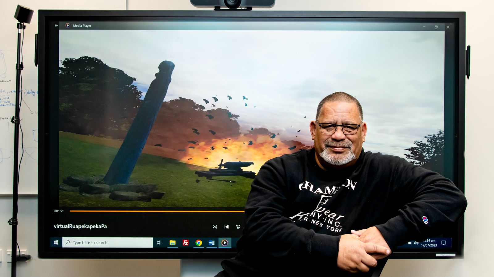 Researcher Kevin Shedlock posed in front of a large television screen displaying a virtual Ruapekapeka Pā