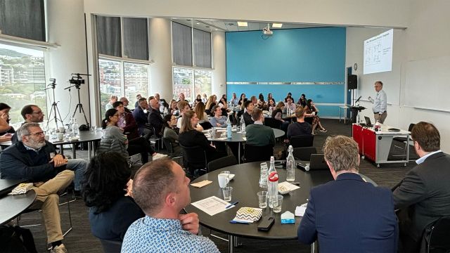 Attendees in conference room watching a speaker.