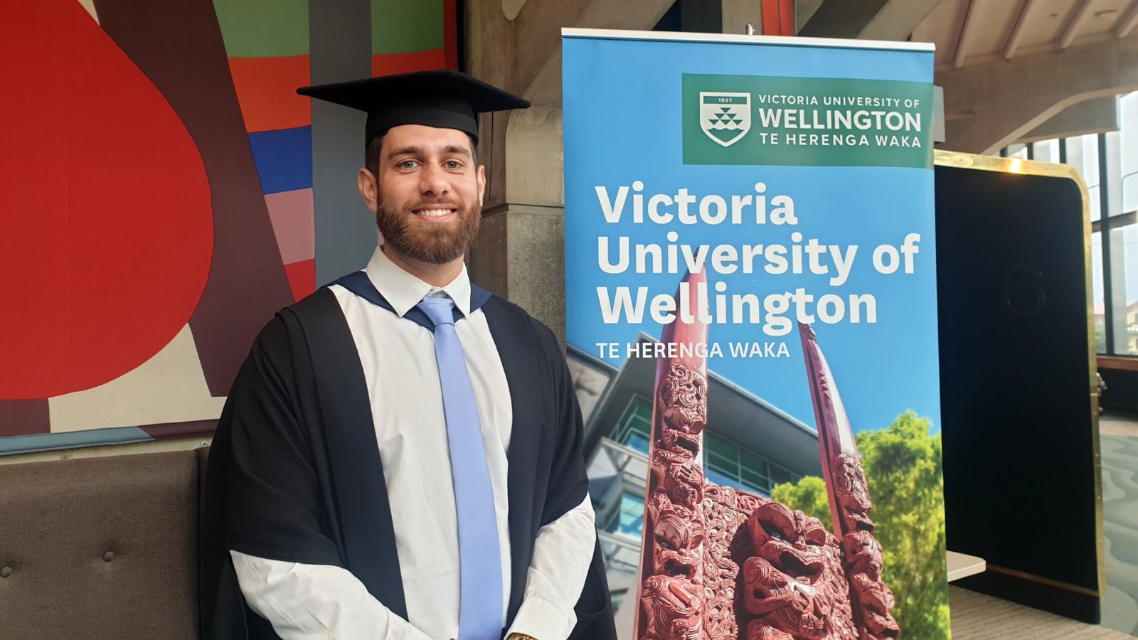 Sohail posing for a photo in his academic dress at graduation