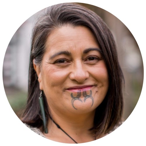 Māori woman with dark brown hair and moko smiling
