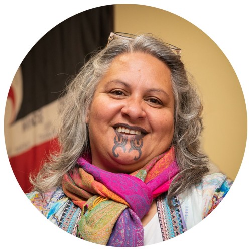 Māori woman with grey hair and moko smiling.