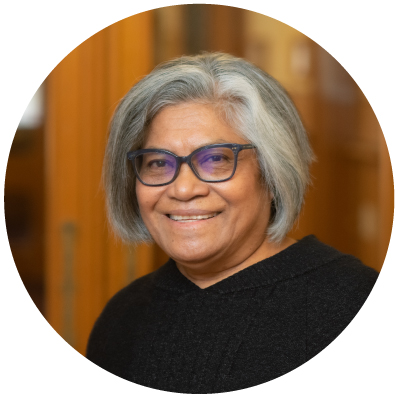Pasifika woman with grey hair and glasses smiling 