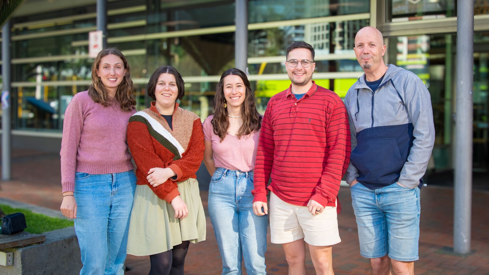 Photo of colleagues standing in front of VUW with arms around each other