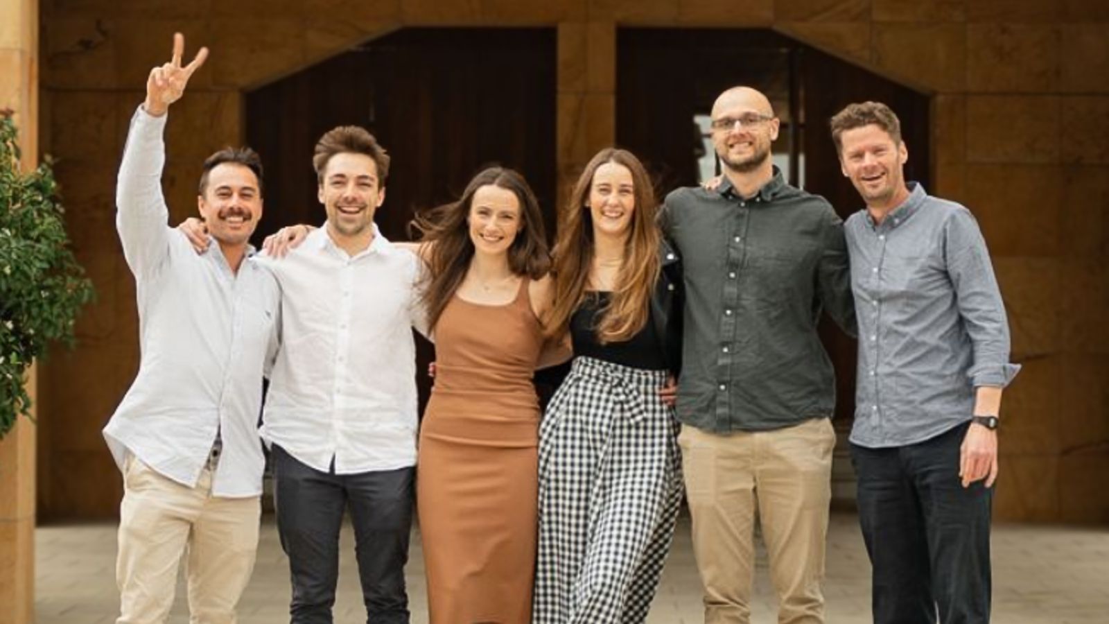 Team of colleagues with arms around each other celebrating