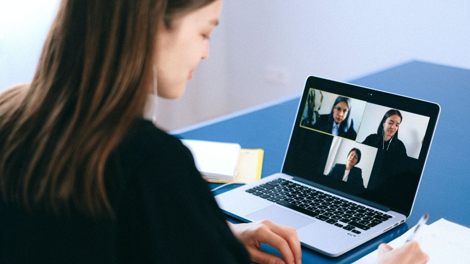 female with long hair looking at computer screen with three women in boxes on it