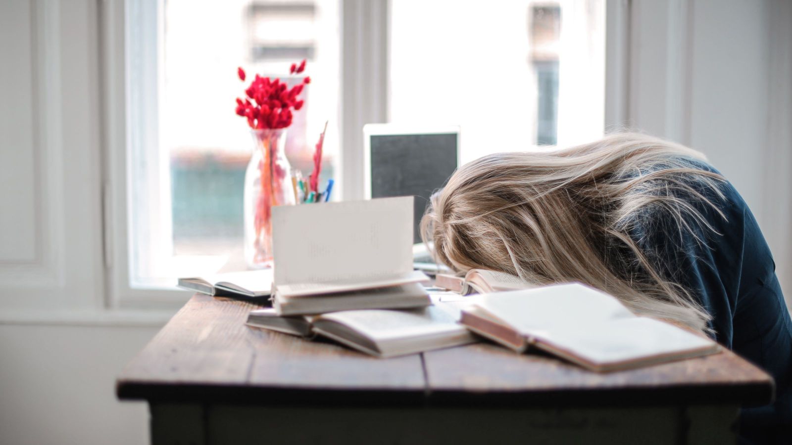 girl with head in books and looks to be sleeping