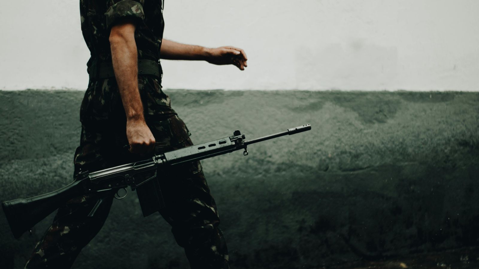 Man in army uniform carrying a gun