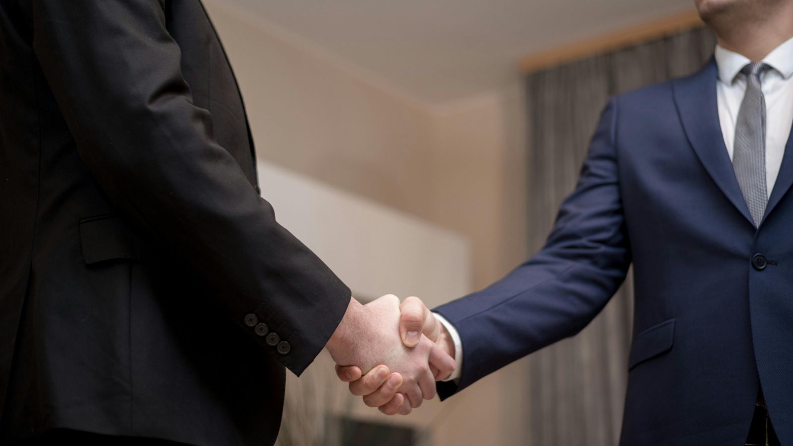 Two people in suits shaking hands 