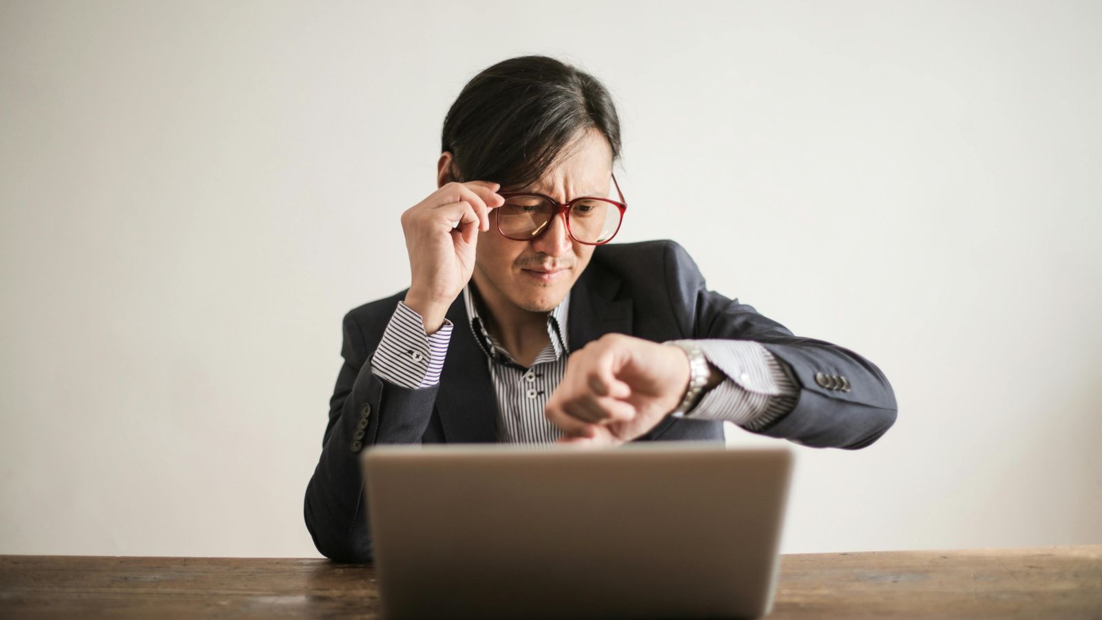 Person with laptop open and looking at watch