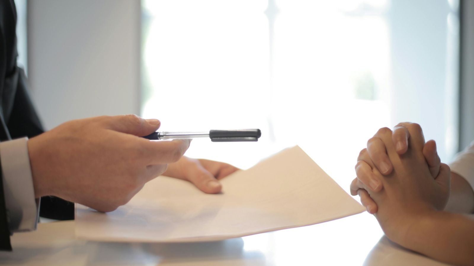 Man handing contract and pen to a woman