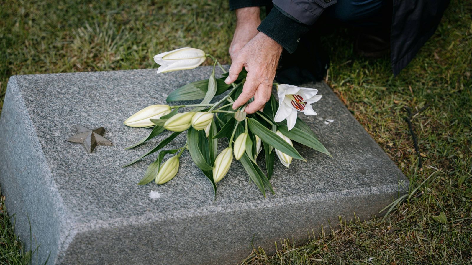 Person putting flowers on a grave 