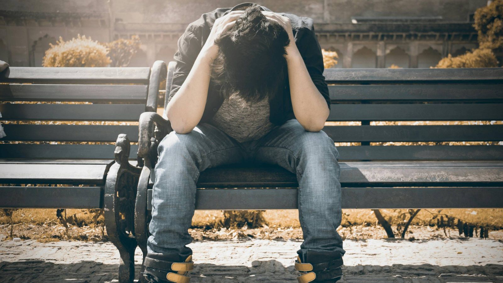 Person sitting on bench with head in their hands 