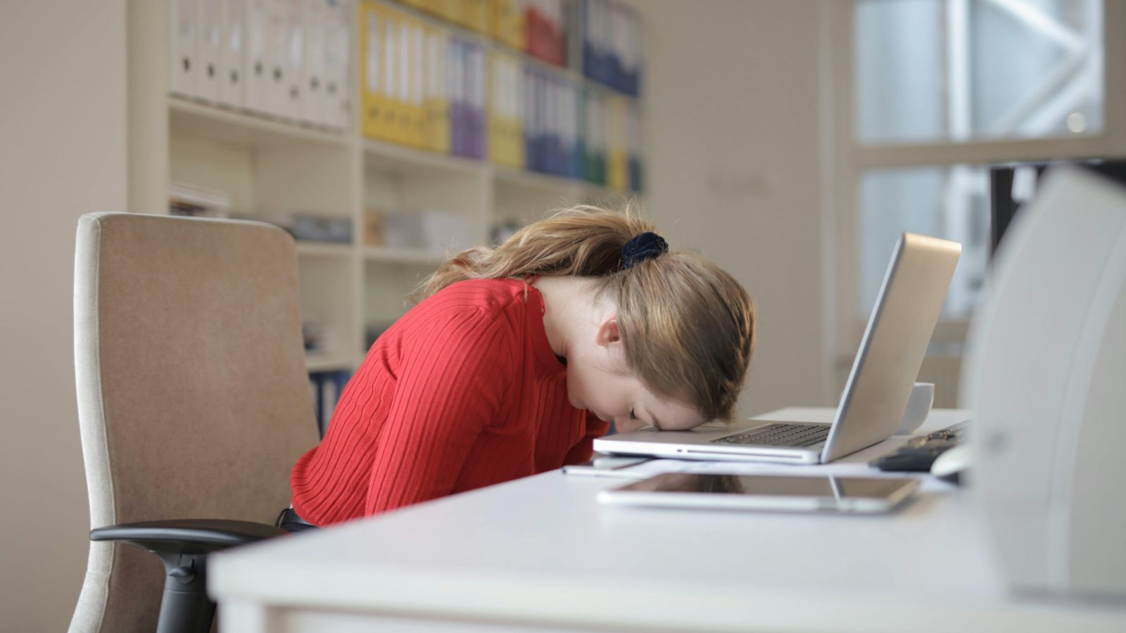 Office worker with head on her desk 