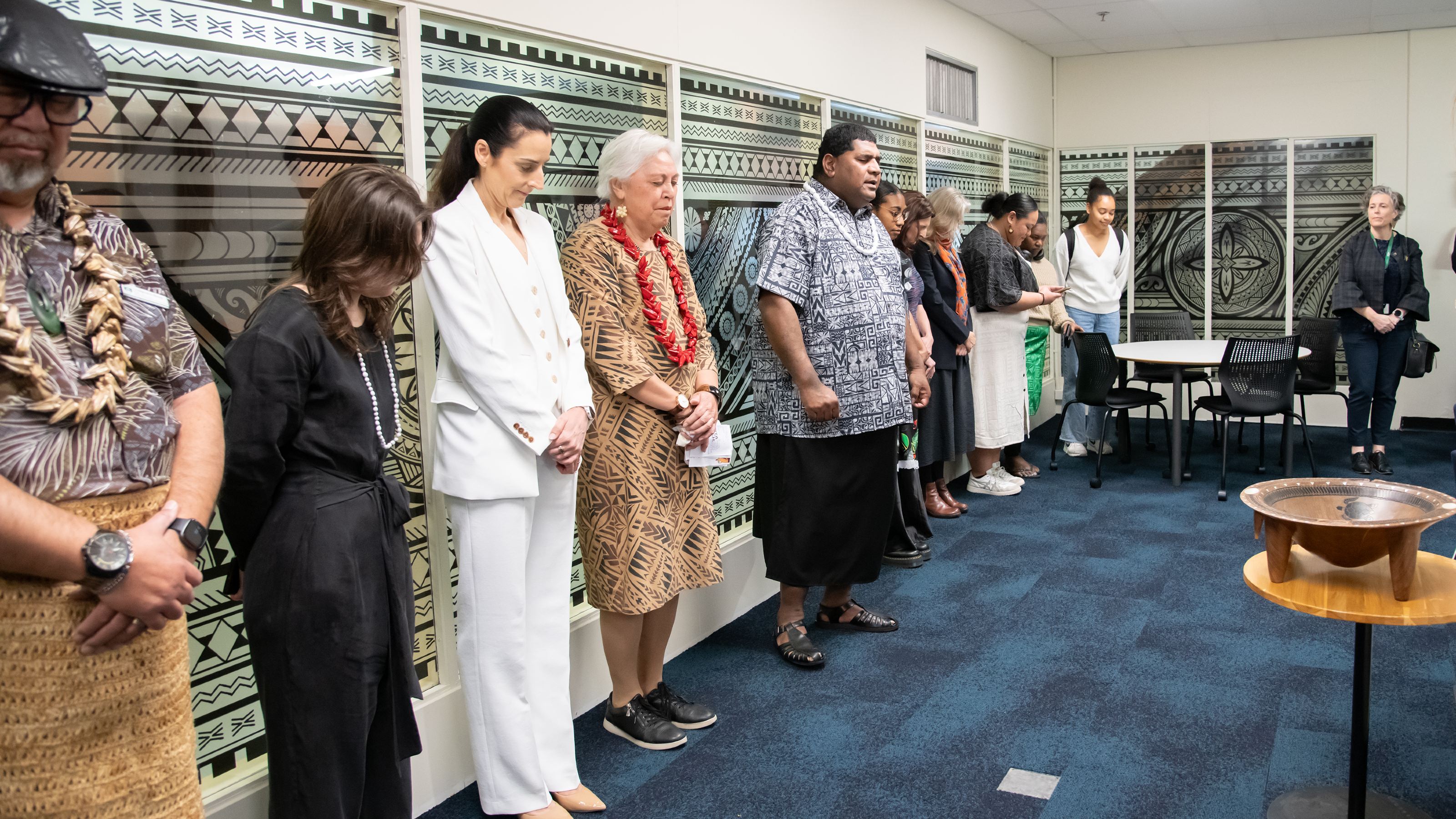 A group of people, heads bowed in prayer, inside Toloa Lapita