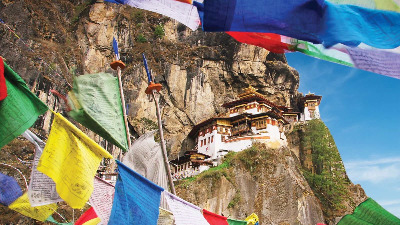 A temple on a hillside, with flags in the foreground