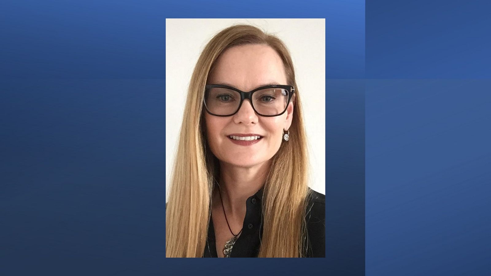 A smiling woman with long hair and glasses