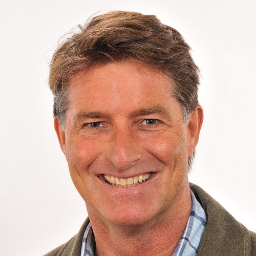 A man with brown hair smiles at the camera