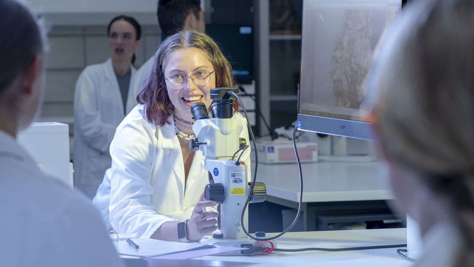 A female student stands behind a microscope.Image copyright Victoria University of Wellington.