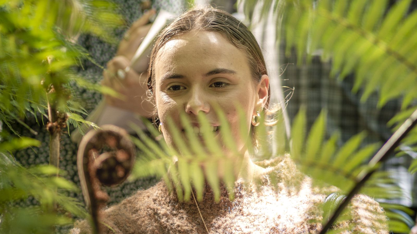 A female postgrad student looks through some ferns