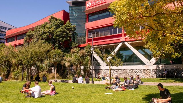 students studying on a lawn in front of Te Aro buildings